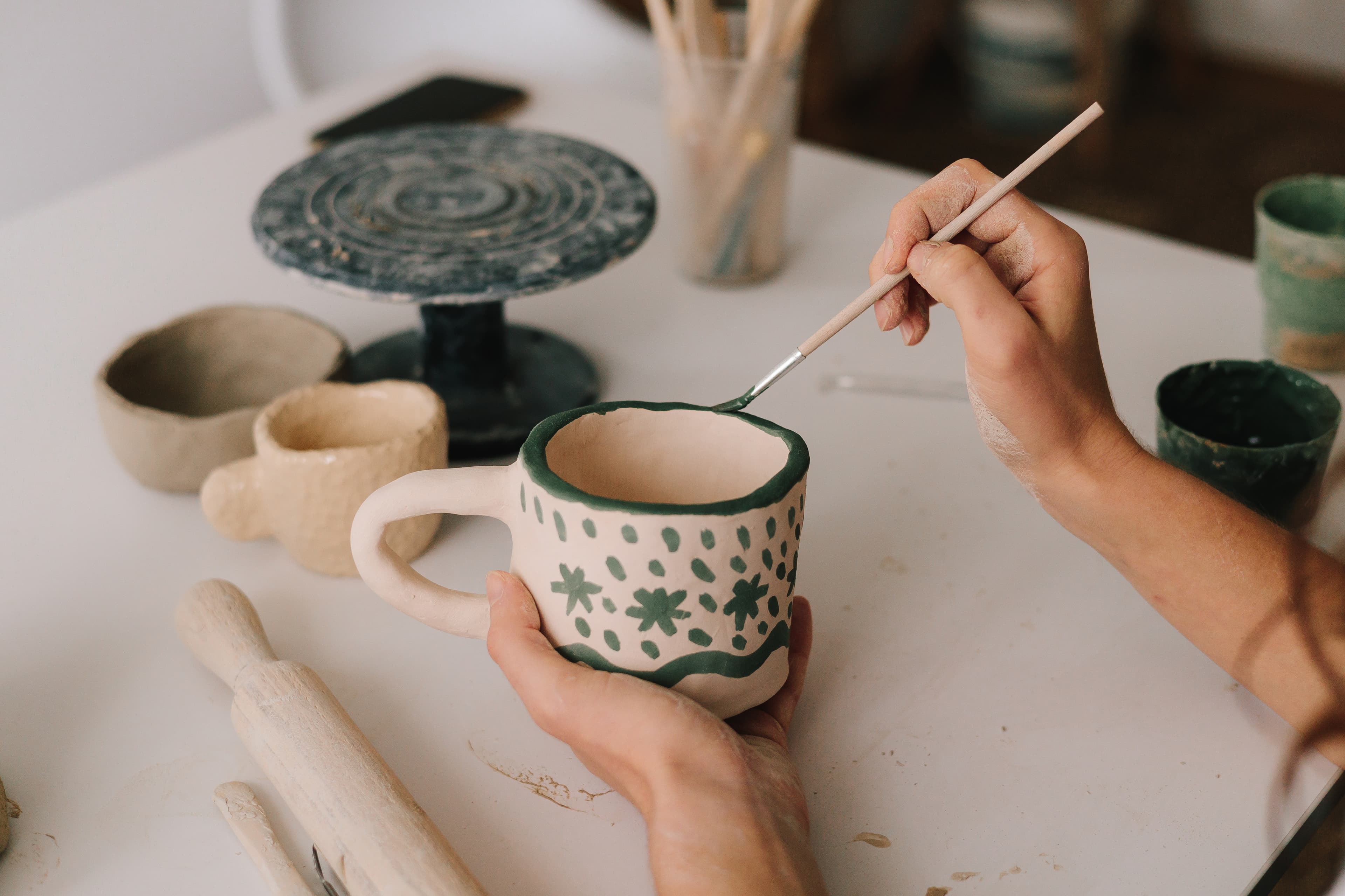 Some hands painting a cup 